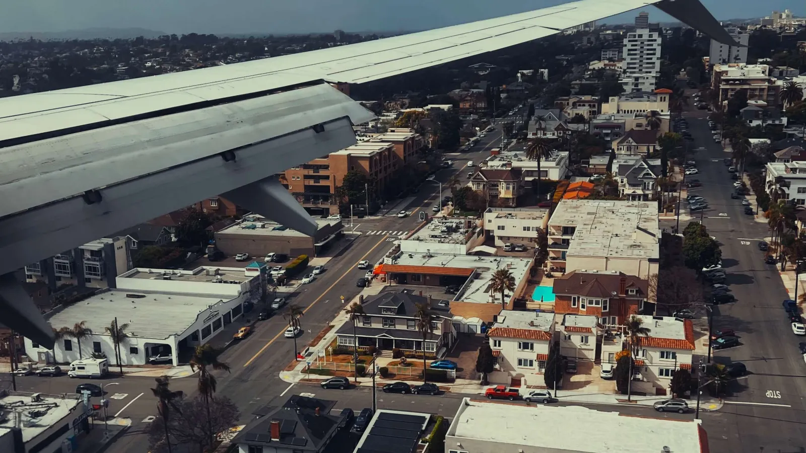 Photo from an airplane window from the window seat right behind the right wing over San Diego, very close to the houses below.